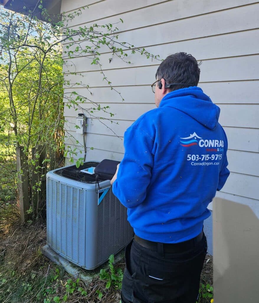 Conrad's technician stands next to a large air conditioning unit